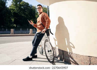 Using a cycling app, a young man riding a bicycle to work is an ecotransport for the city.