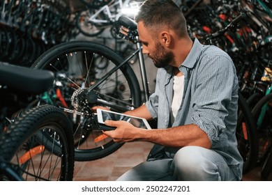 Using digital tablet. Repair man in bicycle shop, working in store. - Powered by Shutterstock