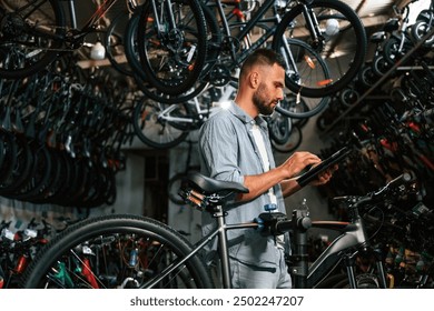 Using digital tablet. Repair man in bicycle shop, working in store. - Powered by Shutterstock