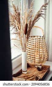 Using Dried Natural Various Grass Plants Inside Vase Indoors For Home Decoration. Vase With Various Plants And Wood Black Metal Wire Lantern On Window Sill In Daylight. Copy Space, Room For Text.