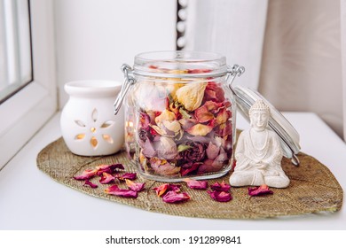 Using Dry Rose Petals To Make Rose Potpourri Which Is Great For Home Scent. Mason Jar Filled With Dry Rose Petals And Puds With Meditating Buddha Figurine And Aroma Lamp With Candle Next To It.