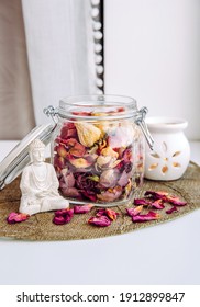 Using Dry Rose Petals To Make Rose Potpourri Which Is Great For Home Scent. Mason Jar Filled With Dry Rose Petals And Puds With Meditating Buddha Figurine And Aroma Lamp With Candle Next To It.