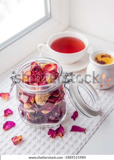 Using dry rose petals to make rose potpourri wich is\
great for home smell. Great way to preserving flowers and memories.\
Mason jar lid open filled with different color rose petals and tea\
cup with tea