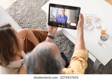 Using eHealth and telemedicine services at home. Senior couple sitting on sofa with digital tablet, having video call with online doctor and getting professional health consultation - Powered by Shutterstock