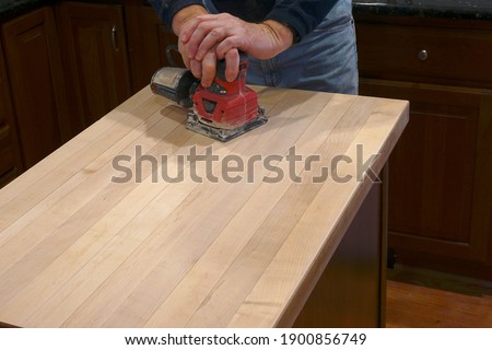 Using an electric sander to refinish a counter top