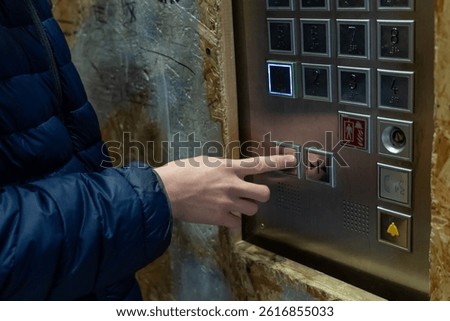 Using an Elevator: A person pressing the close door button in the elevator, illuminated floor selection, utility, transportation
