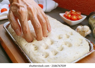 Using fingertips to create dimples in the dough for baking Italian Focaccia Genovese bread