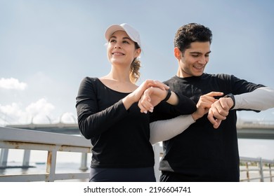 Using a fitness bracelet, a man and a woman doing an active workout running in the city, - Powered by Shutterstock