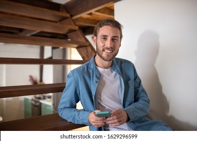 Using gadgets for communication. A smiling young man holding his smartphone