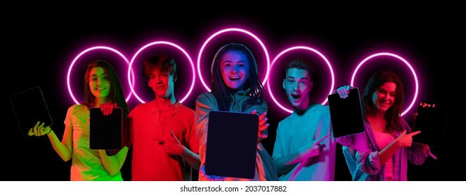 Using gadgets, tablets. Collage made of multiethnic young people standing together isolated on dark background in multicolored neon light with luminescent shape cirlce. Unity, diversity, youth, ad
