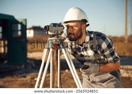 Using the geodetic optical level. Worker is on the construction site at daytime.