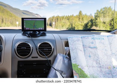 Using A GPS And Paper Road Map On Car Trip. GPS Navigation Drive Assistant And Road Map.  Vacation And Travel In Alberta, Canada