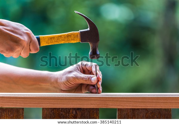 Using hammer\
and nail on wood and bokeh\
background