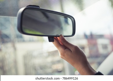 using hand to adjust a rear view mirror in the car before start driving a car for perfect vision and safety in traveling