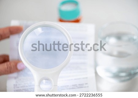 Using a handheld loupe to read small medication instructions. Highlights accuracy, careful review, and responsible medication management.