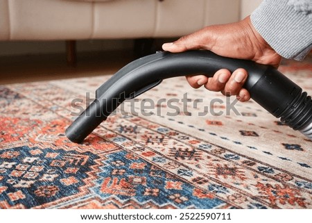 Using a handheld vacuum cleaner to effectively vacuum and clean a colorful area rug thoroughly