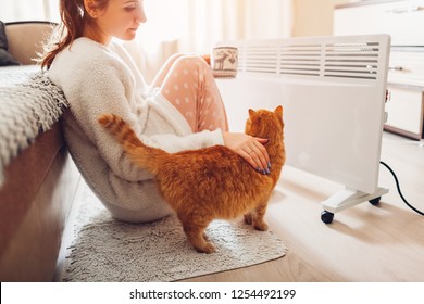 Using Heater At Home In Winter. Woman Warming And Drinking Tea With Cat. Heating Season.