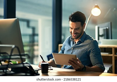 Using his time wisely with smart technology. Shot of a young businessman using a digital tablet during a late night at work. - Powered by Shutterstock