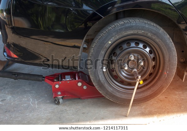 Using the\
jack to lift the car to change the\
tire.