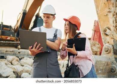 Using Laptop. Two Workers Is On The Borrow Pit At Daytime Together.