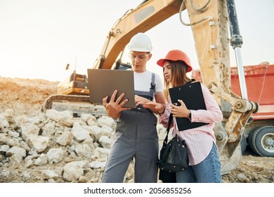 Using Laptop. Two Workers Is On The Borrow Pit At Daytime Together.