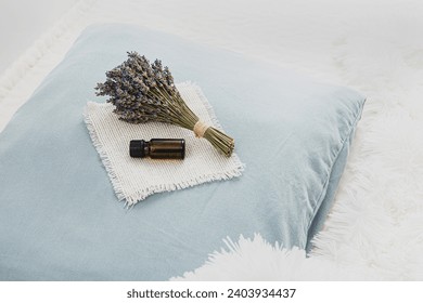 Using lavender flower essential oil for better good night sleep. Calming relaxing aromatherapy concept. Lavender oil and bouquet of lavender flowers on soft pillow in home bedroom. Minimal white.