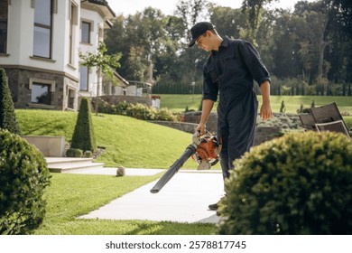 Using leaf blower. Professional gardener is on the lawn.