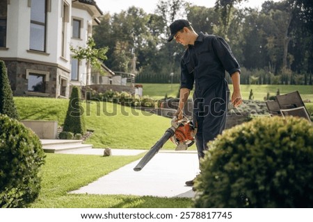 Using leaf blower. Professional gardener is on the lawn.