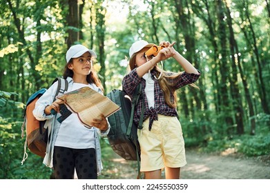 Using the map. Two girls is in the forest having a leisure activity, discovering new places. - Powered by Shutterstock