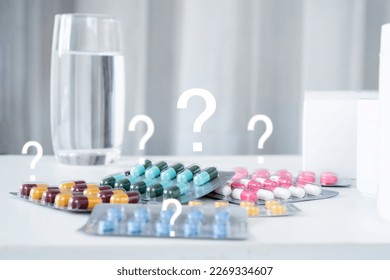 using medicine incorrectly or take wrong dose medicine concept with   pills and glass of water with question mark 