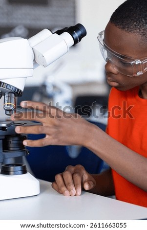 Using microscope, student conducting scientific experiment in school laboratory. research, science, education, biology, analysis, discovery