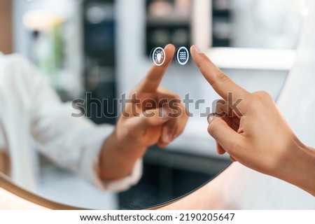 Using the mirror with touchscreen feature. Pretty young woman is in the store of goods for the home.