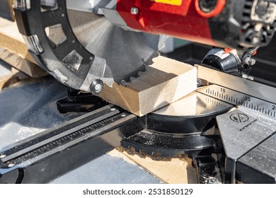 Using a miter saw to cut a piece of wood. Own carpentry workshop. Sawing a wooden board with a miter saw. Safe equipment for the furniture and construction industry. - Powered by Shutterstock