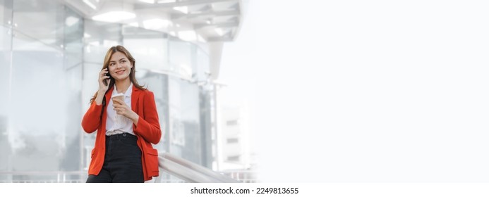 Using mobile, call phone, Smiling young Asia business woman leader entrepreneur in red color suit working outdoor urban street walk. - Shutterstock ID 2249813655