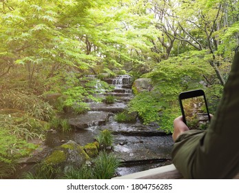 Using mobile device taking picture of beautiful scenery of small waterfall. 