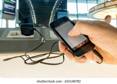 Using A Mobile Phone While Charging The Battery At The Airport. Phone Charging On A Table At Charging Station In The Lobby. Free Charging On The Airport Terminal.