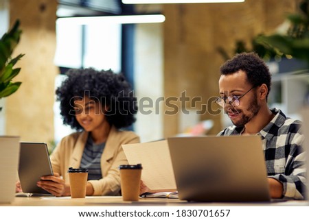 Using modern technologies. Two young multiracial business people sitting at the desk, working together in coworking space