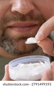 using nicotine pouch background plastic box surface close up of bearded man taking white snus portion swedish tobacco free alternative smokeless product concept of addiction, bad habits, nicotine