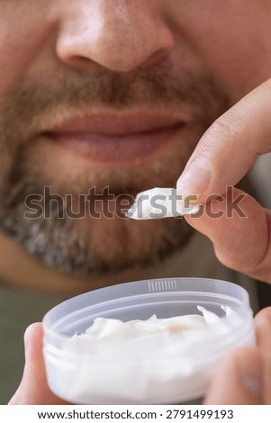using nicotine pouch background plastic box surface close up of bearded man taking white snus portion swedish tobacco free alternative smokeless product concept of addiction, bad habits, nicotine