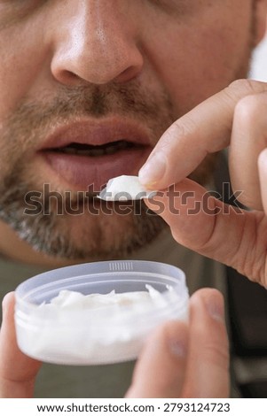 using nicotine pouch background plastic box surface close up of bearded man taking white snus portion swedish tobacco free alternative smokeless product concept of addiction, bad habits, nicotine
