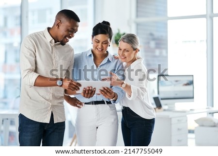 Using online resources to their advantage. Shot of a group of businesspeople using a digital tablet together in an office.