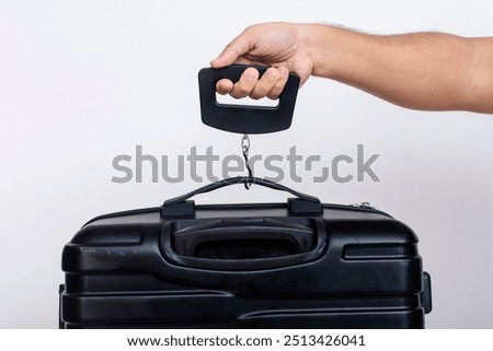 Using a portable hand held digital scale to weigh in carry-on baggage or luggage bag.