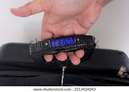 Using a portable hand held digital scale to weigh in carry-on baggage or luggage bag.