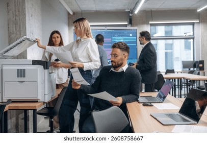 Using printer. Group of office workers are indoors together.
