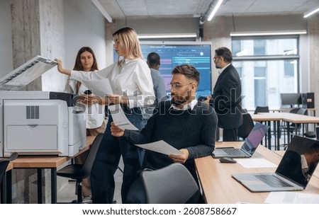 Using printer. Group of office workers are indoors together.
