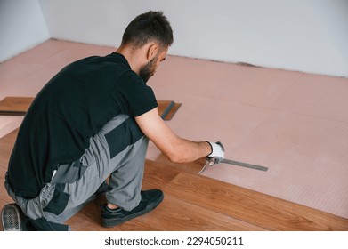 Using the rubber hammer. Man is installing new laminated wooden floor.