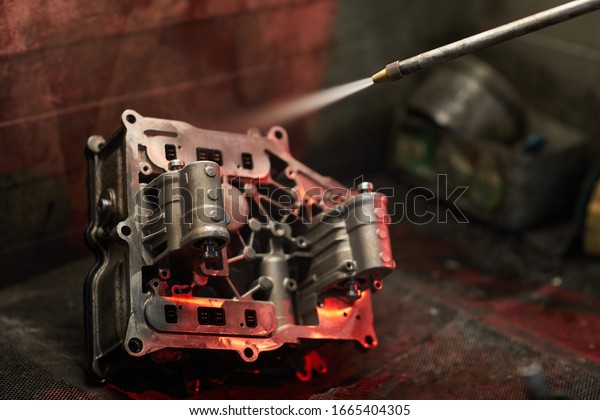 Using sandblast gun to clean dirty car\
engine part, horizontal close up shot, copy\
space