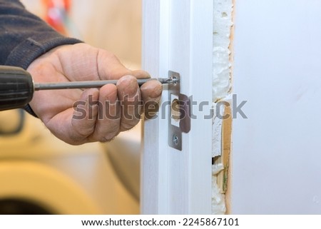 Using screwdriver to install lock in new house an locksmith worker