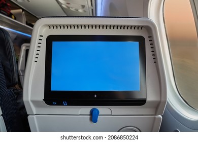 Using the seatback screen on a plane trip, watching movies, displaying flight data. Blank touchscreen in blue.