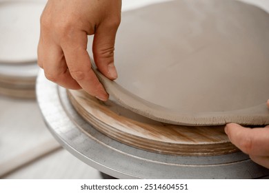 Using a sharp pottery carving knife to cut out a perfect round shape from clay. Ceramics class. Modeling clay into a round form